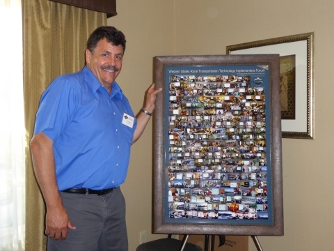Ian Turnbull standing with the framed collage of Forum pictures.