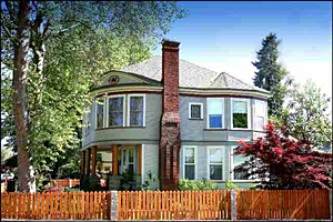 The Stockslager-Farraher House, grey two stories with rounded corners brick chimney in center wooden fence in front