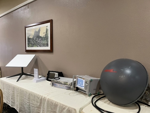 A spectrum analyzer and other communications equipment are displayed on a table.