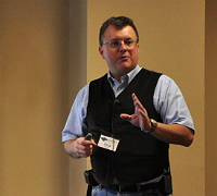 A man speaking with his hand raised gesturing.