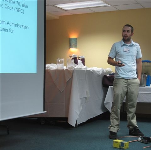 A man standing looking towards a projector screen with a pointer in his hand.