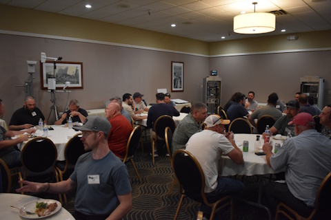 Groups of people eating at round tables. Two ITS cabinets are in the background and a mounted weather station is on the left.